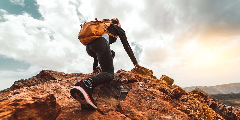 Success woman hiker hiking on sunrise mountain peak - Young woman with backpack rise to the mountain top. Discovery Travel Destination Concept