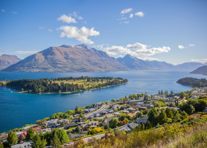 Breathtaking aerial view of Queenstown by Lake Wakatipu, surrounded by majestic mountains under clear skies.